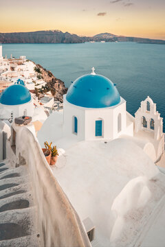 Whitewashed architecture and blue domed churches overlooking the aegean sea during golden hour