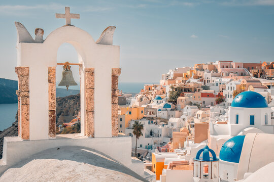 Oia village in santorini island showcasing traditional cycladic architecture with bell towers and blue domes under clear sky