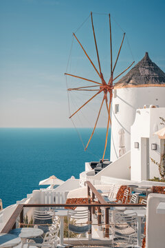 Whitewashed cycladic architecture and an iconic windmill standing against the blue sky and sea