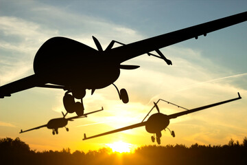 Obraz premium Silhouette of military combat drones against the sunset
