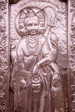 A silver-plated metal sculpture depicting Dattatreya, a three-headed, multi-armed Hindu deity, holding a trident and a lotus. Shri Durgiana Temple in Amritsar.