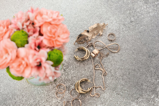 Lovely arrangement with flowers and jewelry on a stone surface during daytime