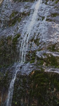 Close up of water flowing down wet mossy stone wall in Wasserlochklamm gorge, Palfau, Austrian Alps