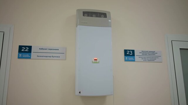 Hospital corridor wall features air recirculator unit between closed office doors. Clean hallway setup creates professional clinical mood