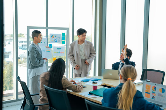 Co worker member raises hand during business presentation while speaker explains financial dashboard. Interactive discussion improves participation, communication, planning, teamwork, decision making.