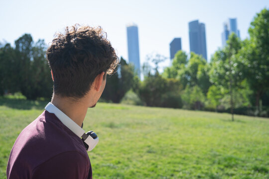 Young person gazing at the city skyline from a park with skyscrapers in the background