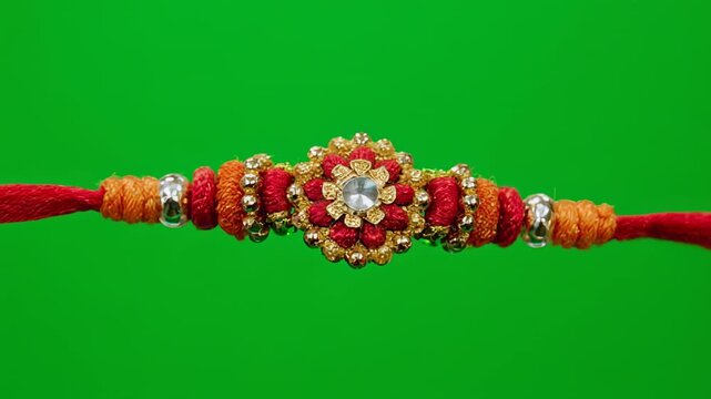 Ornamental Rakhi bracelet with red thread on green screen background for Indian festival celebration