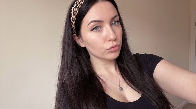 Confident young woman close-up selfie portrait with leopard print headband and natural makeup