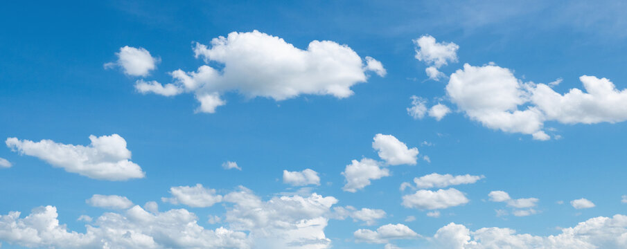 Soft white clouds drift across a bright blue sky