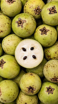 Fresh white sapote background with halved fruit revealing creamy flesh and black seeds