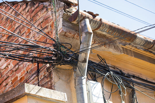 Tangled Utility Cables on Weathered Urban Building Facade