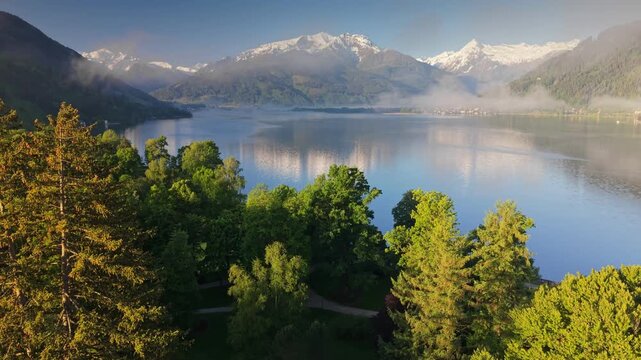 Aerial view of Zell am See lake with snow capped Alps, fresh morning landscape in Austria. Snow-capped Alpine peaks reflecting in Zell am See lake. Pristine mountain lake Zell am See at early morning