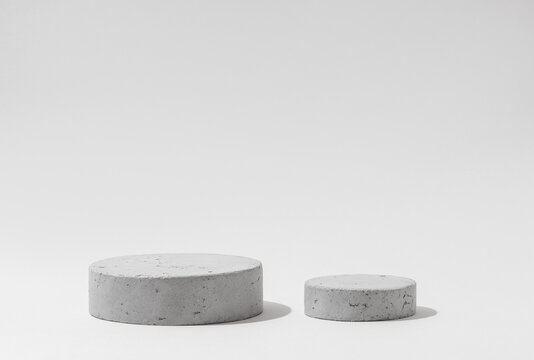 Two Concrete Cylinder Podiums of Different Sizes on Light Gray Background with Copy Space for Product Mockups.