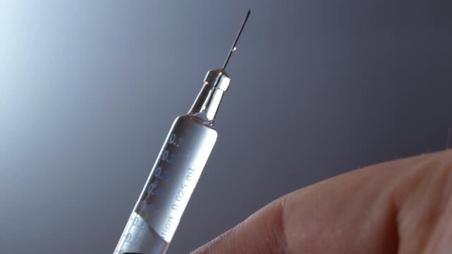 medical syringe deflation until liquid droplet appears on needle tip against white background (version left)