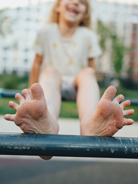 A child's bare feet on a horizontal bar in summer, in focus with bokeh. Children's foot health.