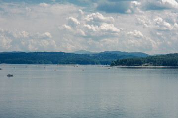 A cloudy sky over a mountain lake with boats floating on it. Lake Solina, Bieszczady. © Tomasz