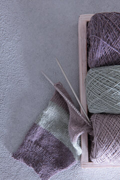 Knitting process: skeins of yarn in wooden box and finished fabric. Cozy photo of creative process of knitting. Hobbies and creativity. Slow living. Home and comfort. Hobby and handicraft concept