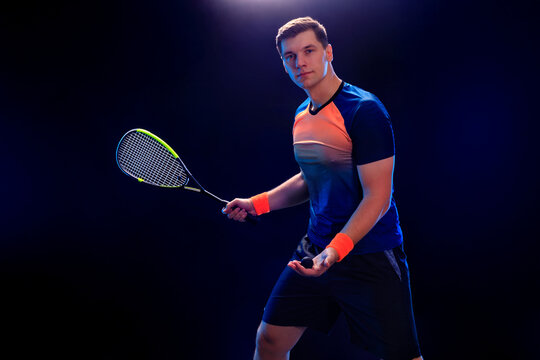 Squash player on a squash court with racket. Man athlete with racket on court with neon colors. Sport concept.