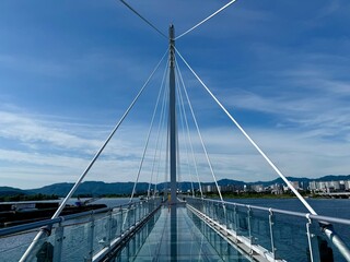 Fototapeta premium Soyanggang Skywalk, a bridge-like walkway of transparent glass with steel railings, jutting out into Uiam Lake. Blue sky in the summer
