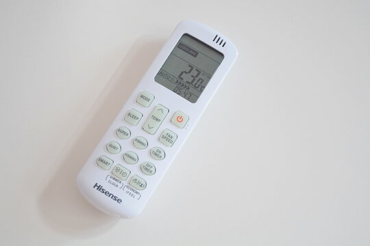 Hisense white air conditioner remote control lying on light background with display showing cooling mode and temperature
