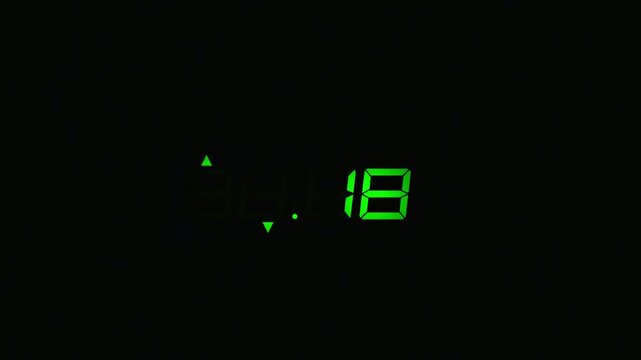 Green digital led clock display showing numbers counting down in darkness countdown time