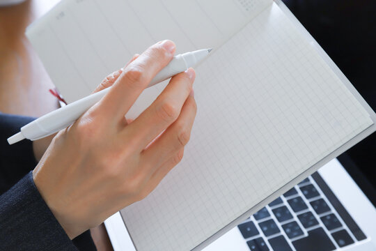手帳とペンを持った女性の手元　ビジネス