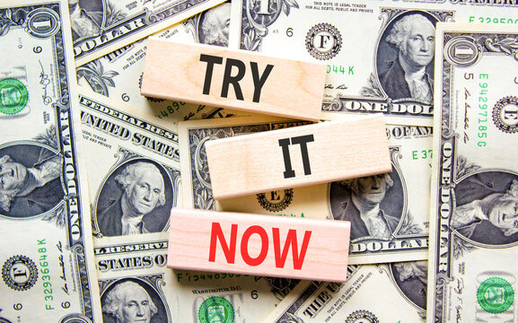 Try it now words symbol. Concept words Try is now on beautiful wooden blocks. Beautiful dollar bills background. Dollar bills. Business support motivational and try is now concept. Copy space.