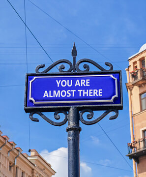 You are almost there symbol. Concept words You are almost there on beautiful road sign. Beautiful blue sky buildings background. Business You are almost there motivational support concept. Copy space
