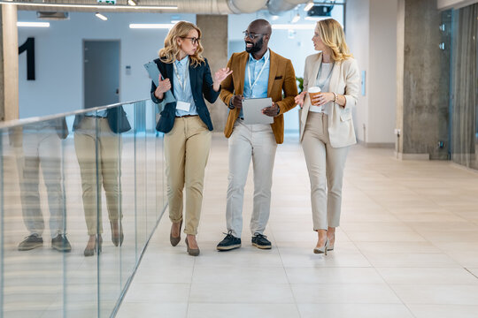 Business people discussing ideas while walking in a modern office space during the day