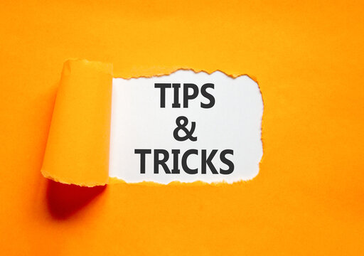 Tips and tricks words symbol. Concept words Tips and tricks on beautiful white paper. Beautiful orange background. Business tips and tricks motivational support concept. Copy space.