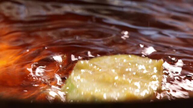 Deep frying battered eggplant and acacia pennata omelet slices in hot oil pan for spicy shrimp paste dip at Bangkok.