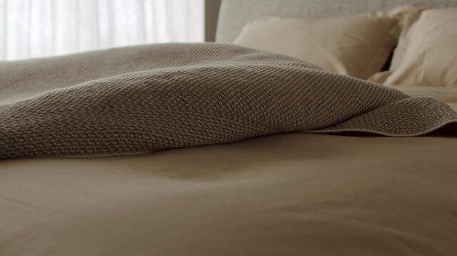 Beige blanket elegantly draped on a neat bed in a serene bedroom, evoking tranquility and comfort. The soft lighting adds warmth, making it a perfect setting for relaxation and rest.Cozy Beige Blanket