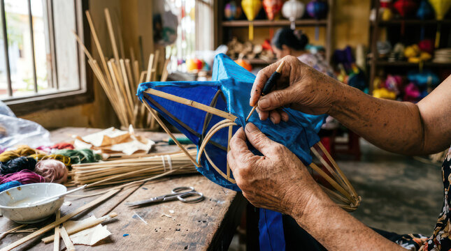 Hands crafting a blue lantern with bamboo and fabric.