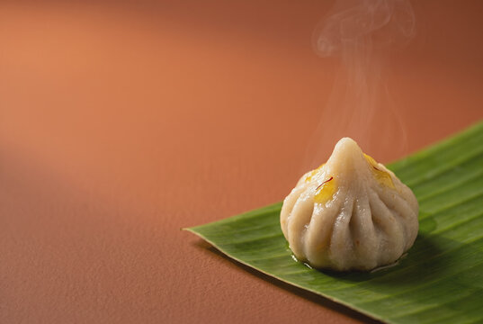 Single freshly steamed ukadiche modak served on a banana leaf with saffron garnish