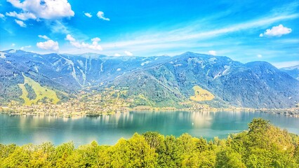Obraz premium Scenic view of Thumersbach village and Lake Zell with alpine mountains, Austria