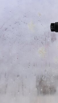 Housemaid steam cleaning window in room. Removing a New Year sticker. Vertical video