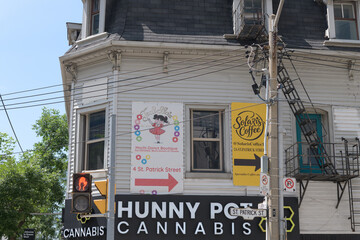 Fototapeta premium historic building with signs including that of Hunny Pot Cannabis at 198 Queen St W, northwest corner of St Patrick St, Toronto