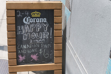 Fototapeta premium a-frame sidewalk chalkboard sign with Corona brewery sponsored signage outside a pub on Queen West, Toronto