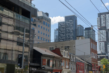 Fototapeta premium wide view of Welcome to Queen West sign and buildings, Toronto