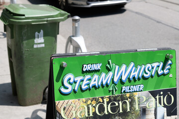 Fototapeta premium Steam Whistle brewery branded a-frame sign outside a pub on Queen West, Toronto