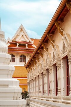 ow angle view of intricate white Thai temple facade with golden gables and traditional orange roof tiles