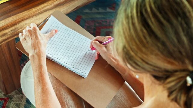 Hand, pen and writing in a notebook sitting at a gazebo on the backyard. Woman, schedule and appointment with a female employee.