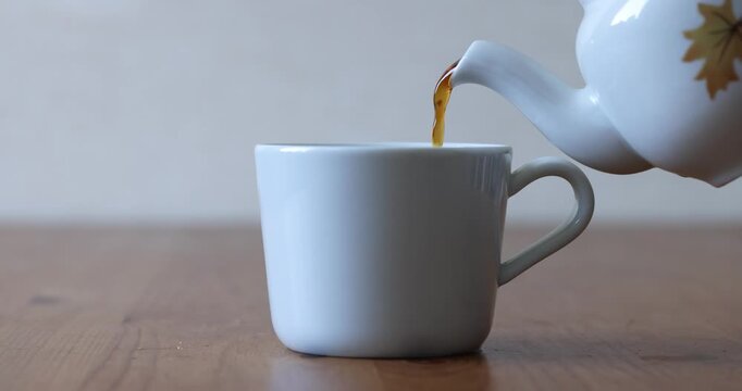 Pouring Black Tea Infusion into Ceramic Cup Side View Real Time