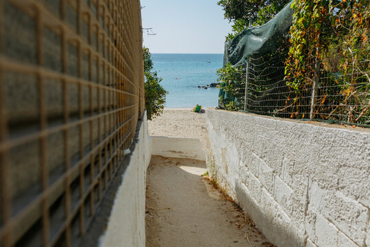 Narrow Pathway Leading to a Sandy Beach and Calm Mediterranean Sea