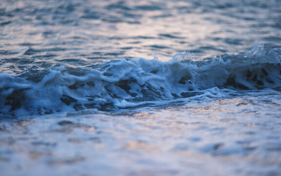 Landscape image of sea wave splashing on beach before sunset