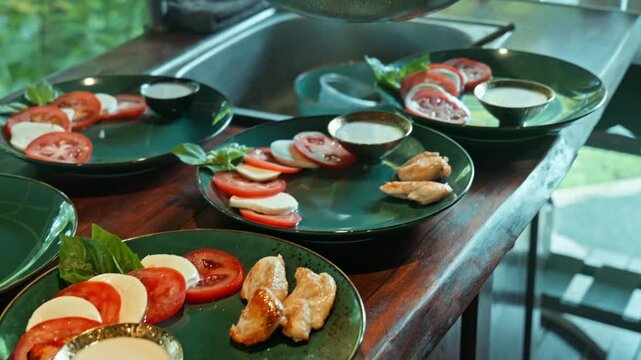 Caprese salad with ripe tomatoes, mozzarella cheese and fresh basil leaves on dark wooden boards. Close up with a chicken.