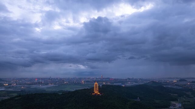 Time-lapse scenery of dark clouds rolling over the Listening Wind Tower at dusk
