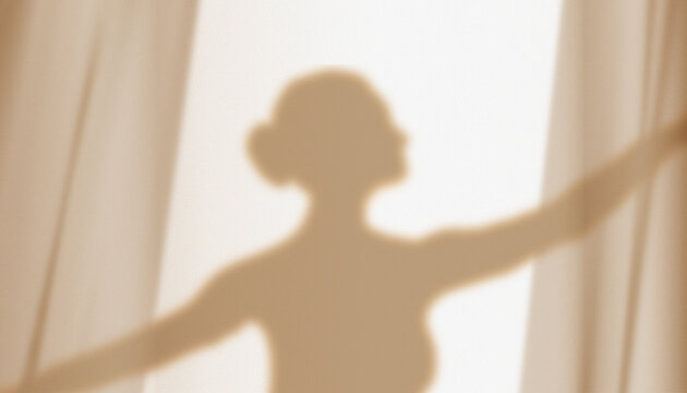 Silhouette, shadow on the wall of a graceful ballerina dancing behind curtains.