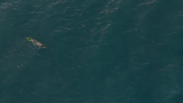 Having spread the net in the sea, the fishermen now haul it back onto their wooden boat, hoping eagerly for a plentiful catch of fish

