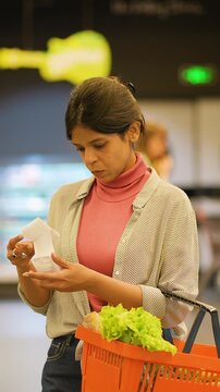 Indian woman checking long shopping receipt in supermarket